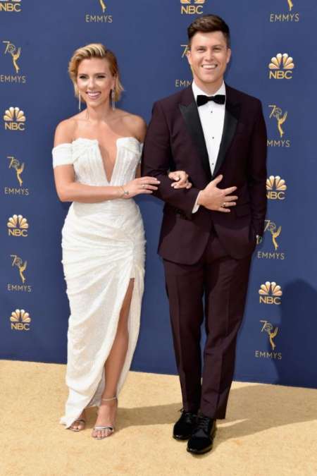 Colin Jost, presentador de la gala, sonriente junto a su pareja Scarlett Johansson (Balmain)